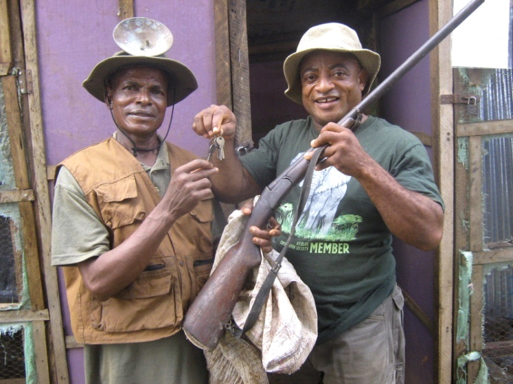 WCS education coordinator, Mark Otu (right), hands over the keys of a snail pen to one of the project beneficiaries, John Kidze, as he receives hunting gear from him (© WCS)