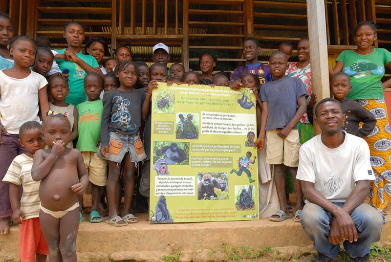 Gemeindemitglieder präsentieren ein Poster, das erklärt, wie man sich bei der Begegnung mit einem Gorilla verhält.)